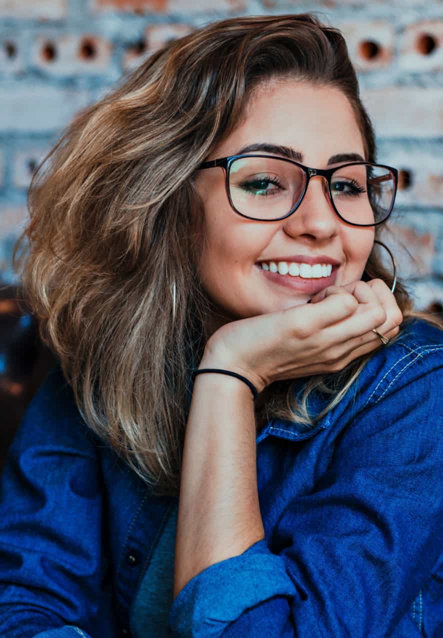 Young woman with brown hair in front of a brick wall